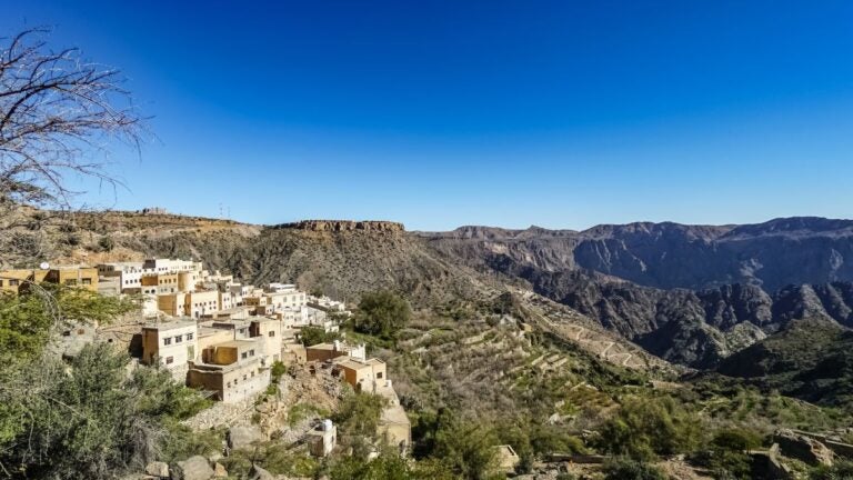 Een traditioneel bergdorpje gebouwd op de rotsachtige hellingen van Jebel Akhdar in Oman onder een strakblauwe lucht.