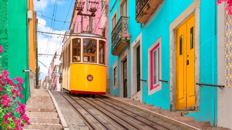 De iconische gele kabeltram in een smalle, kleurrijke straat van Lissabon, een onvergetelijk hoogtepunt tijdens de beste stedentrips Europa.