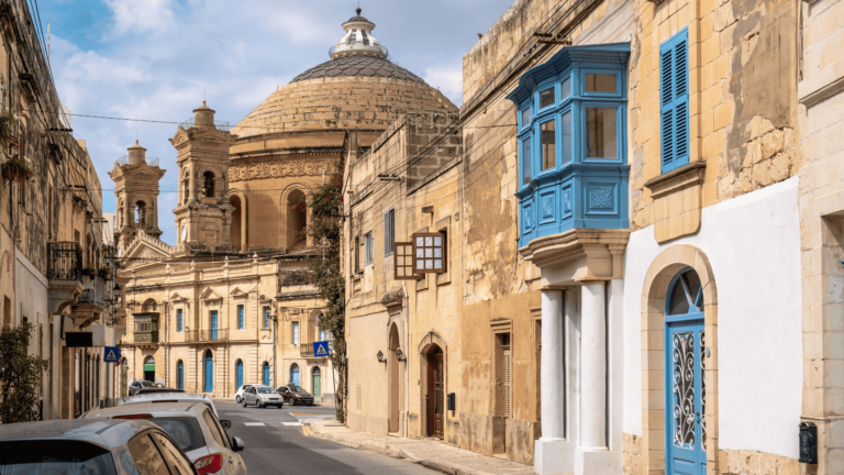 Een authentieke straat in Malta met de Mosta Dome op de achtergrond, een van de bekendste bezienswaardigheden op Malta