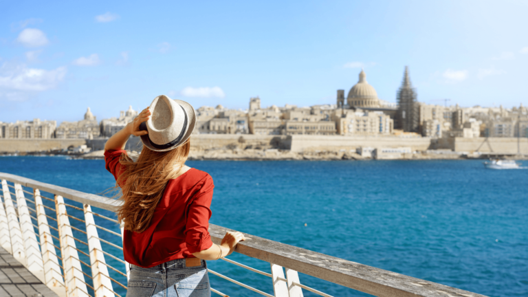 Vrouw bewondert de skyline van Valletta vanop de promenade in Sliema