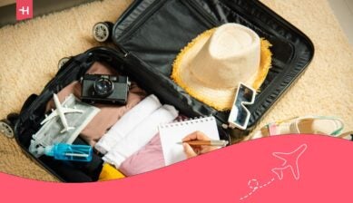 Een open koffer met reisitems zoals een camera, kleding en een strohoed voor een reis naar Sri Lanka