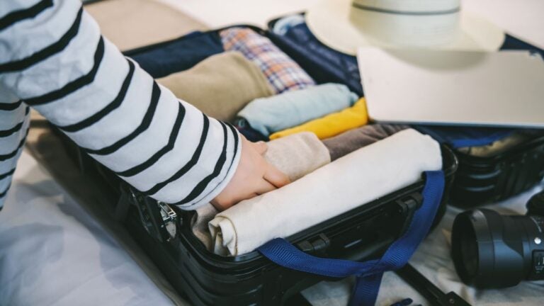 Iemand die kleding oprolt en inpakt in een koffer voor een reis naar Zuid-Afrika