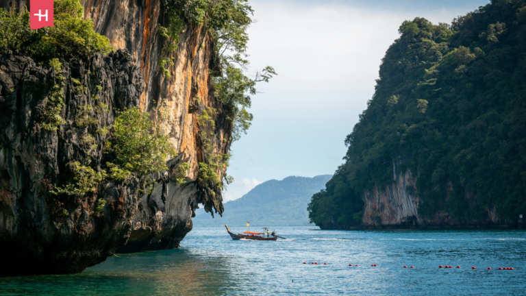 Boot vaart tussen twee steile rotsformaties in Thailand