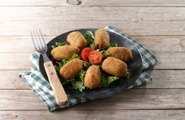 Spaanse kroketten op een bord met sla en tomaat, een geliefd hapje uit de spanje eten traditie