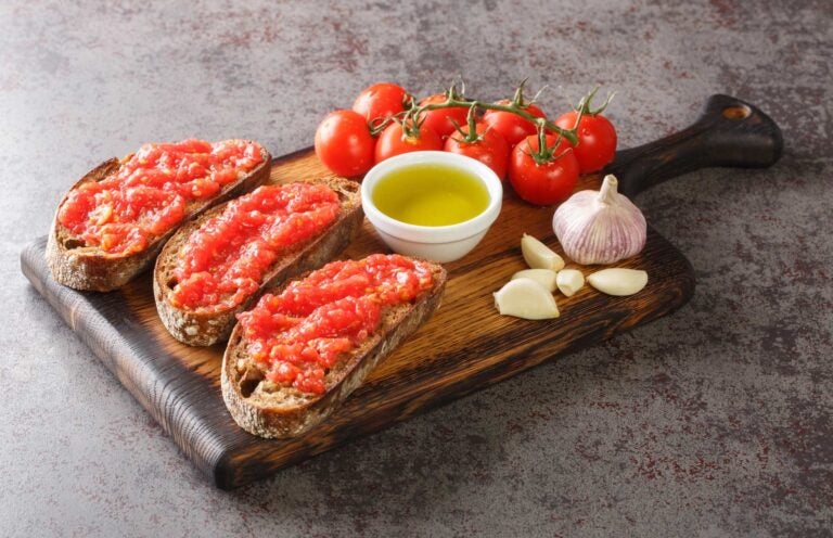 Pan con tomate met verse tomaten, knoflook en olijfolie op een snijplank, een eenvoudig maar iconisch spanje eten gerecht