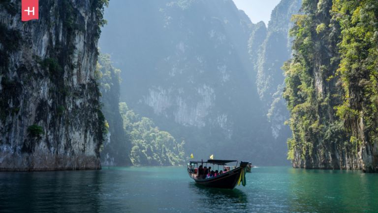 Een boot vaart op de Thaise wateren, geflankeerd door karstformaties