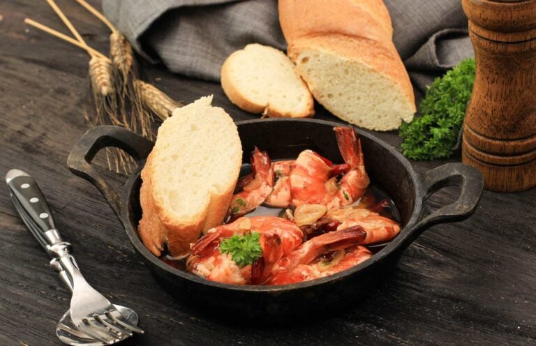 Gambas al ajillo met knoflook en brood in een gietijzeren pan, een populaire tapa uit de spanje eten cultuur