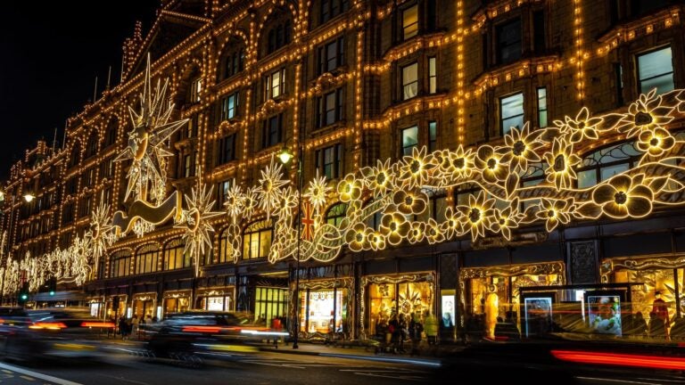 Verlichte etalage van Harrods in Londen tijdens de avond met luxe decoraties en winkels.