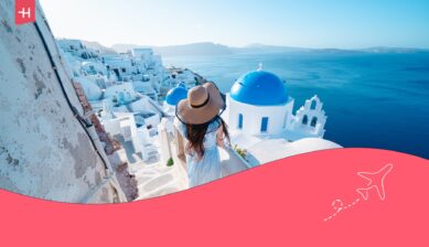 Vrouw kijkt uit over de blauwe koepels van Santorini, een van de mooiste eilanden van Europa