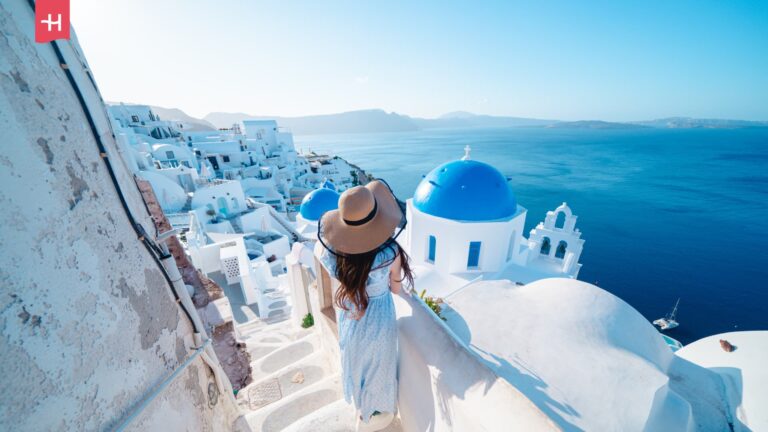 Vrouw kijkt uit over de blauwe koepels van Santorini, een van de mooiste eilanden van Europa