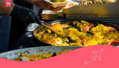 Kok serveert verse paella met zeevruchten op een markt, een symbool van de rijke spanje eten cultuur