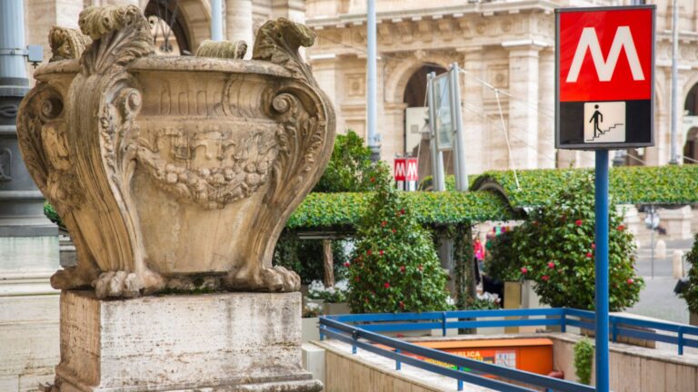 Ingang van een metrostation in Rome naast een historisch gebouw.