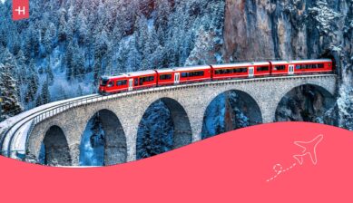 Rode trein rijdt door een besneeuwd Zwitsers landschap als uitgelichte afbeelding voor een artikel over een treinreis door Europa