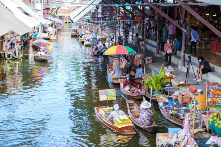 Verkopers verkopen eten en producten vanuit boten op de drijvende markt van Damnoen Saduak in Thailand.