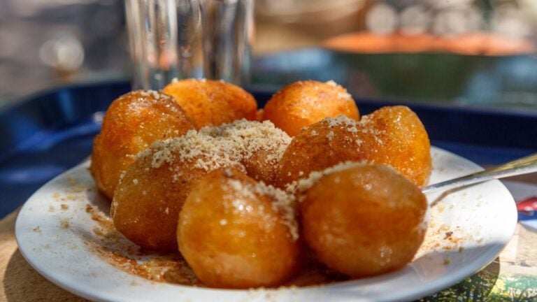 Loukoumades, Griekse deegballetjes met honing en gemalen noten op een bord.