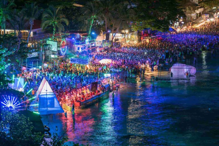 Drukke Full Moon Party op Koh Phangan met kleurrijke verlichting aan het strand.