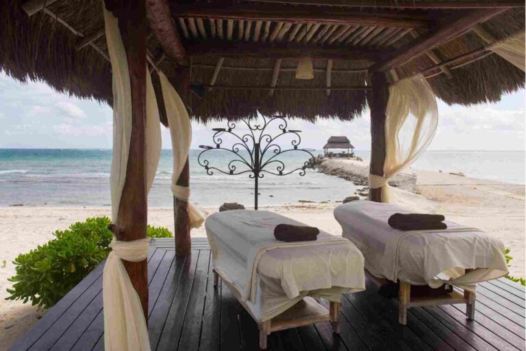 Twee massagebedden in een open strandpaviljoen met uitzicht op zee in Thailand.