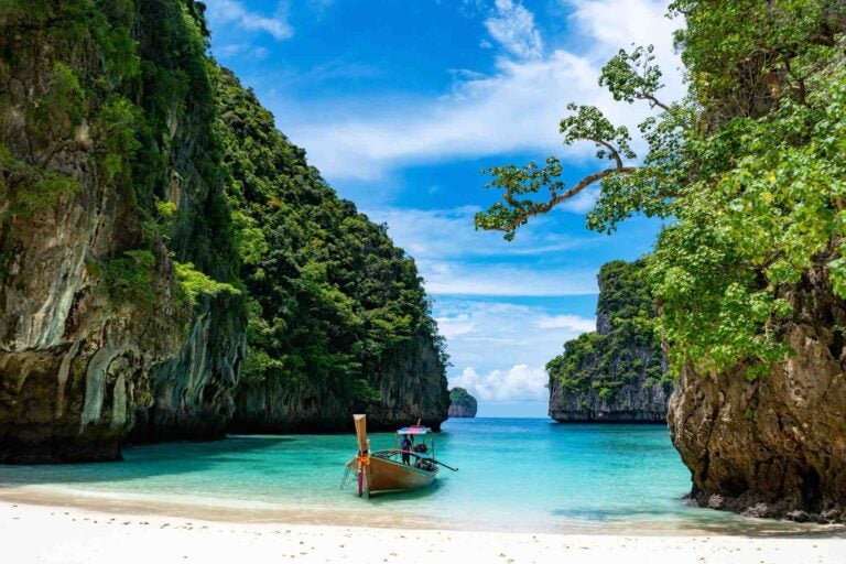 Longtailboot bij Maya Bay op Phi Phi Leh, met turquoise zee en kalkstenen kliffen.