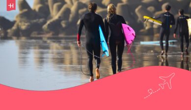 Surfers lopen met hun surfplank over het strand als uitgelichte afbeelding voor een artikel over surfen in Marokko