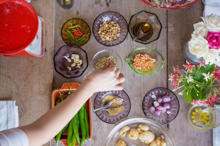 Ingrediënten voor een Thaise kookcursus, waaronder chilipepers, knoflook, garnalen, sjalotten en kruiden.