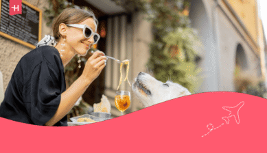 Vrouw eet pasta op het terras met haar hond