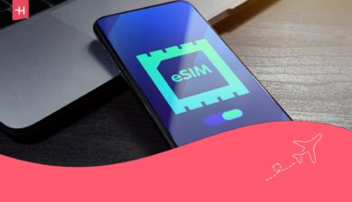 Närbild på en smartphone som ligger på ett träbord med en eSIM-ikon på skärmen som utvald bild för en Airalo eSIM-recension