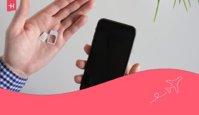 Person som håller en telefon i ena handen och ett SIM-kort i den andra som utvald bild för en artikel om bästa SIM-kortet utomlands