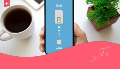 Person som håller en telefon med orden ”SIM” och ”eSIM” på skärmen, med en kaffekopp och en växt i bakgrunden, som utvald bild för en Yesim-recension