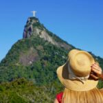 ブラジル・リオデジャネイロのコルコバードの丘に立つキリスト像を遠くから見上げる女性旅行者
