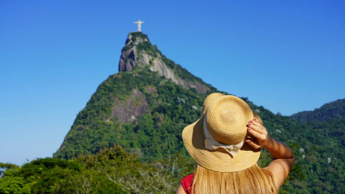 ブラジル・リオデジャネイロのコルコバードの丘に立つキリスト像を遠くから見上げる女性旅行者