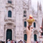 イタリア・ミラノのドゥオーモ前で、アイスクリームを持ちながら写真を撮る旅行者