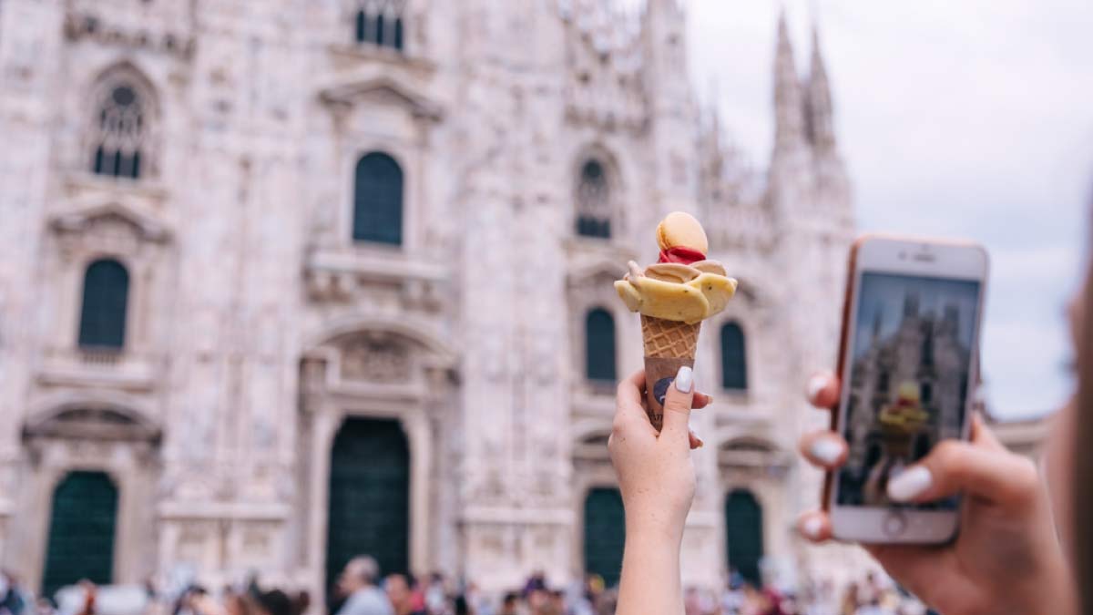 イタリア・ミラノのドゥオーモ前で、アイスクリームを持ちながら写真を撮る旅行者