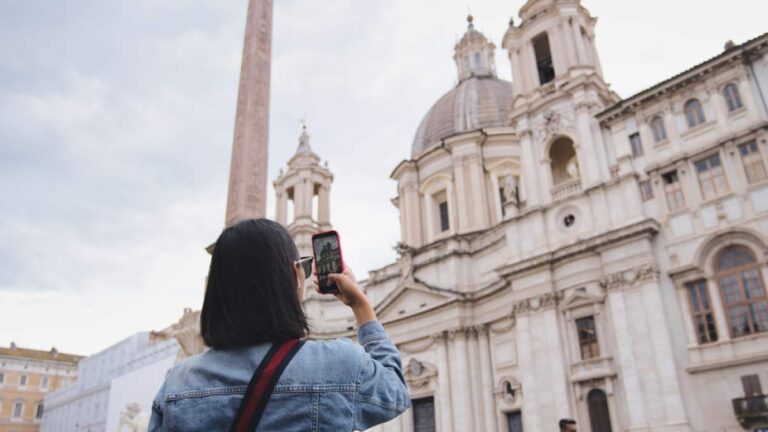 イタリア・ローマのナヴォーナ広場で、歴史的な教会をスマートフォンで撮影する旅行者