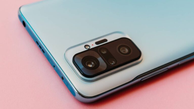 ピンクの背景に置かれたスマートフォンの背面カメラ部分。洗練されたデザインと先進的なカメラユニットが印象的。