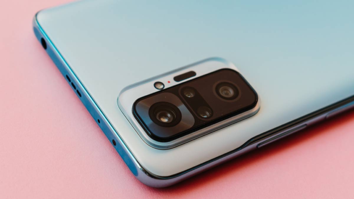 ピンクの背景に置かれたスマートフォンの背面カメラ部分。洗練されたデザインと先進的なカメラユニットが印象的。