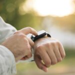 屋外でスマートウォッチの画面を操作する男性の手元