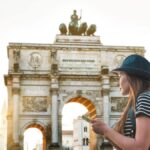 ドイツ・ミュンヘンのジークトーア(勝利の門)の前で、地図アプリを見ながら観光する女性