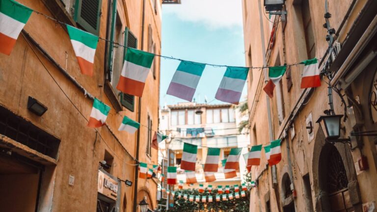 イタリア国旗が並ぶ石造りの建物に囲まれたイタリアの旧市街の路地