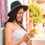 カラフルな街並みにてスマートフォンを操作するアジア人女性旅行者
