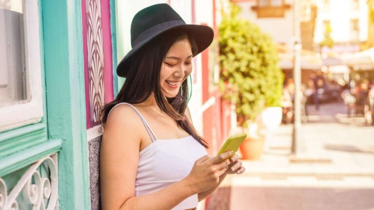 カラフルな街並みにてスマートフォンを操作するアジア人女性旅行者