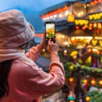 台湾・九份で夜景をスマートフォンで撮影する女性旅行者の後ろ姿
