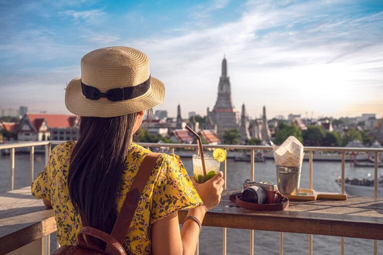 タイ・バンコクで夏服を着てワット・アルンを眺める女性旅行者