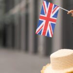 イギリス旅行をイメージした、スーツケースの上に帽子を置き、ユニオンジャックの小旗を持つ手元の風景