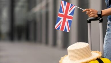イギリス旅行をイメージした、スーツケースの上に帽子を置き、ユニオンジャックの小旗を持つ手元の風景