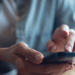 スマートフォンで連絡先を確認・入力する手元のクローズアップ。