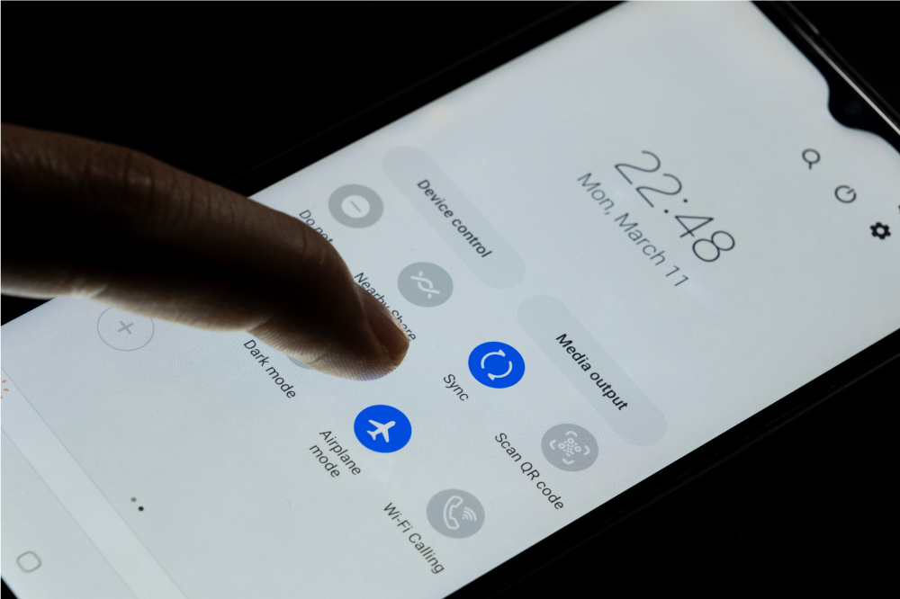 スマートフォンの設定画面で「機内モード」ボタンに触れている指