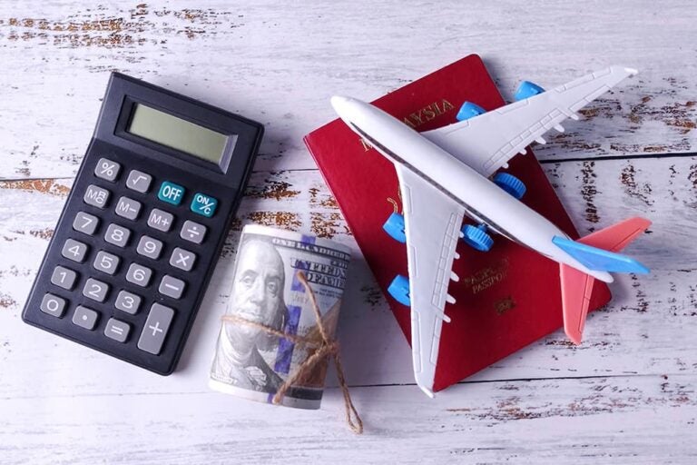 航空券や現金、パスポート、電卓を並べてハワイ旅行の費用や予算を確認するイメージ