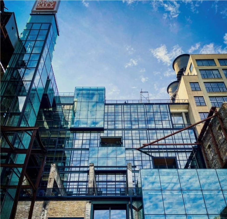 ミネアポリスのミル・シティ・ミュージアムの外観。ガラスとレンガを組み合わせたモダンな建築が特徴で、青空と雲がガラスに映り込み、現代的なデザインと歴史的な要素が融合している。