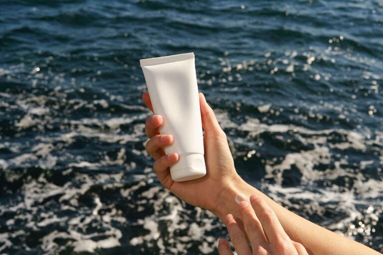 海辺で手に日焼け止めを塗る様子。ハワイ旅行であると便利なアイテム