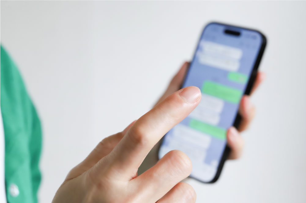 スマートフォンでメッセージアプリを操作している手のクローズアップ写真。